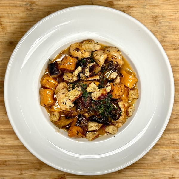A white plate of GOOMAH's Italian gnocchi with butternut squash, mushrooms, and croutons.
