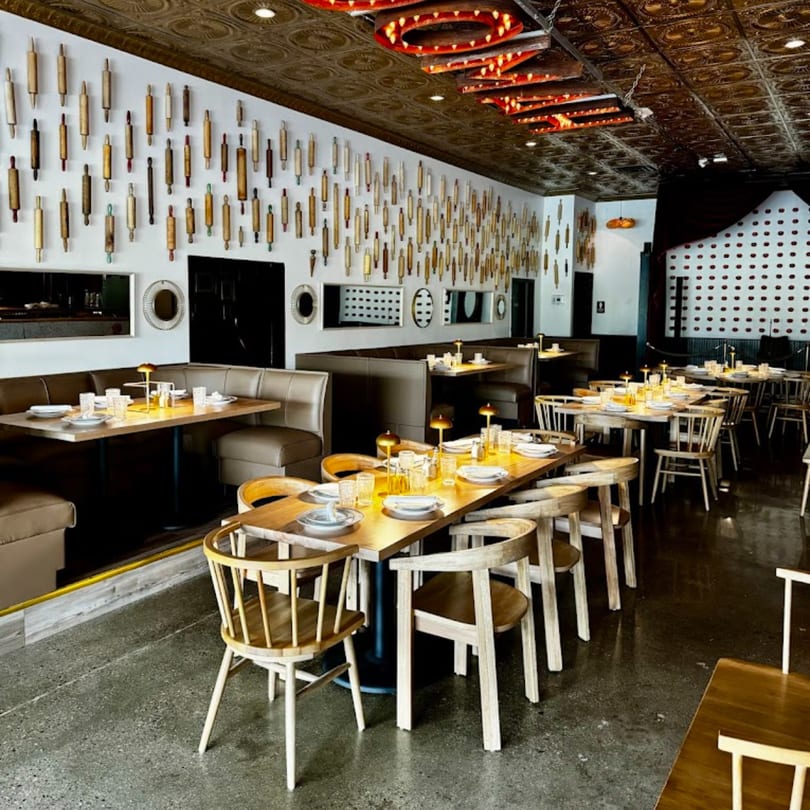 GOOMAH restaurant interior with tables, chairs, booths, and rolling pins decorating the wall.