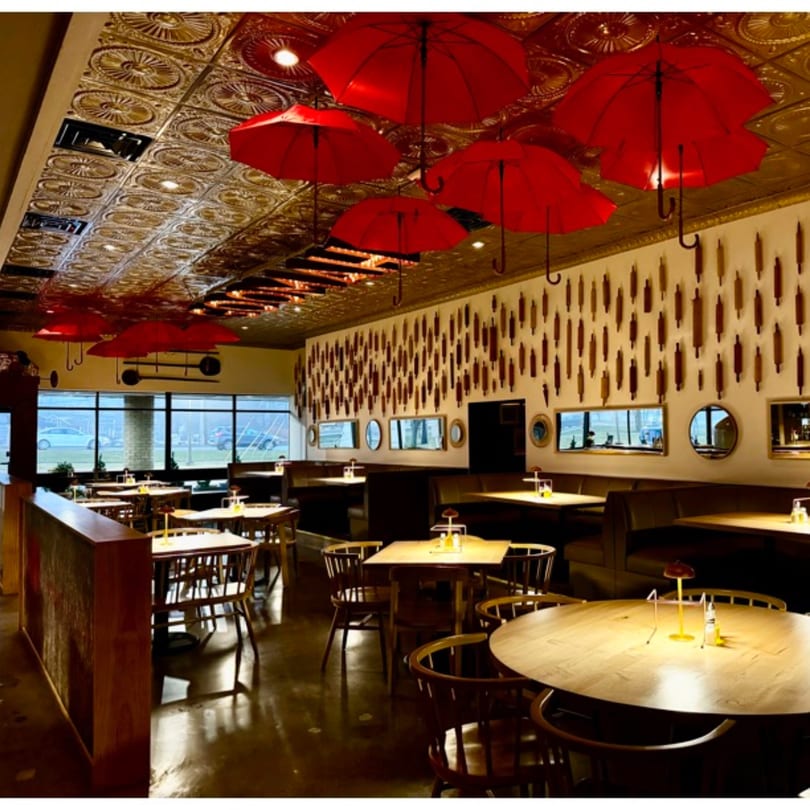 GOOMAH restaurant interior with red umbrellas hanging from the ceiling and wooden tables.
