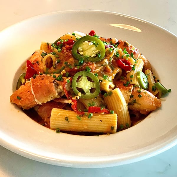 Rigatoni pasta with lobster, red peppers, and sliced jalapeños in a creamy sauce.